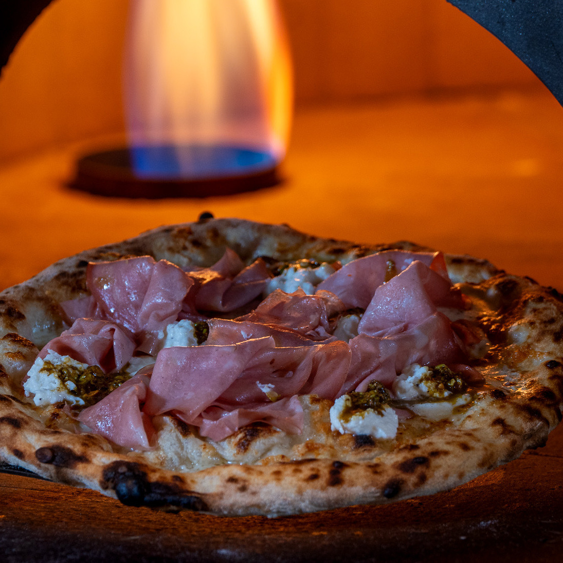 The signature gourmet pizza with creamy burrata & mortadella cheeses paired with crunchy pistachios.